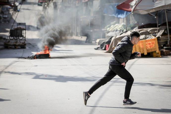 16 February 2025, Palestinian Territories, Ramallah: A man seeks shelter from tear gas fired by Israeli troops during an Israeli military raid in the old town of Nablus in the occupied West Bank. Photo: Ayman Nobani/dpa