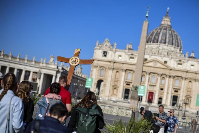 22 April 2025, Vatican, Vatican City: A group of German pilgrims carrying a wooden cross and praying on the way to St. Peter's Basilica. The Argentine pontiff, who led the Catholic Church since 2013, passed away on Easter Monday at the age of 88, leaving 