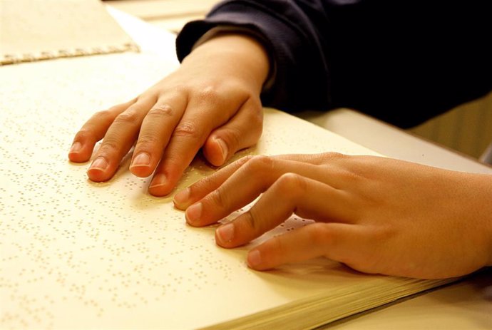 Archivo - Un niño lee un libro en braille. 