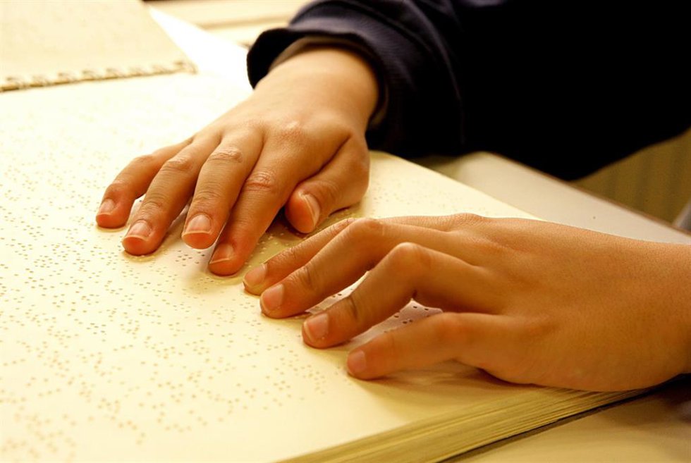 Archivo - Un niño lee un libro en braille. 