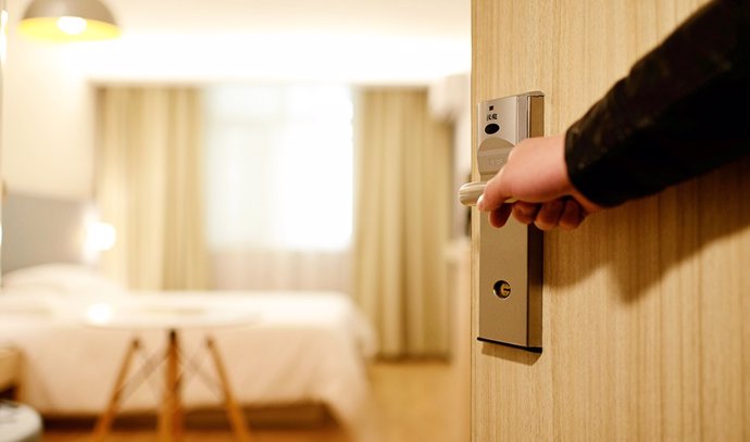 Archivo - Imagen de una usuaria abriendo la puerta de su habitación de hotel.