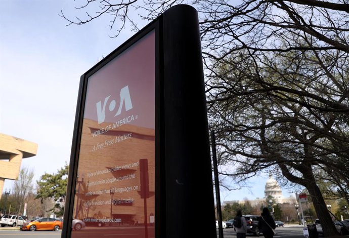 Archivo - 23 de março de 2025, Washington Dc, Virgínia, EUA: O Capitólio dos EUA é visto com uma placa da Voz da América (VOA) em uma janela de vidro em frente ao prédio da VOA em 23 de março de 2025, em Washington, DC. Seis jornalistas da Voz da América 