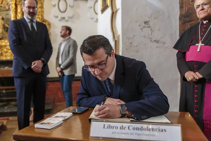José María Bellido escribe en el libro de condolencias por el Papa Francisco, observado por Adolfo Molina y Demetrio Fernández.