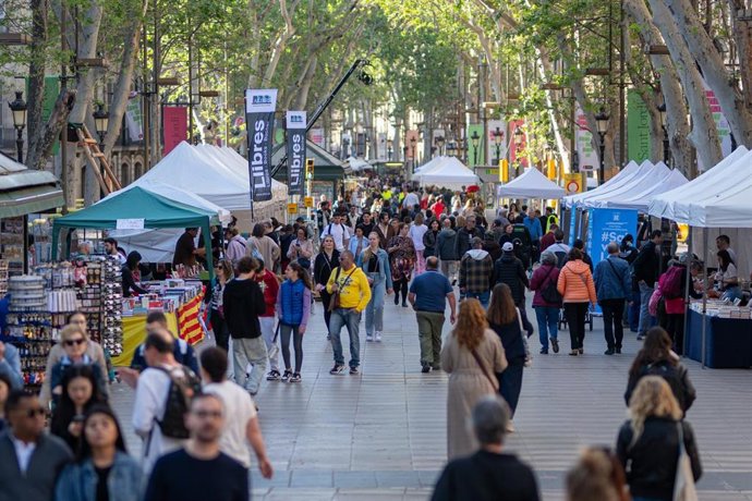 Grupos de personas paseando por las calles y viendo libros durante la Diada de Sant Jordi 2025, a 23 de abril de 2025, en Barcelona