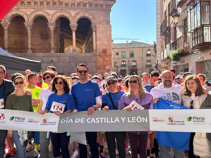 Varias autoridades locales con otros ciudadanos, sujetan la cinta de salida de la marcha y carrera solidaria.