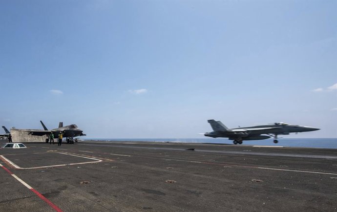 11 de abril de 2025, Mar Vermelho, Estados Unidos: Um avião de caça F/A-18F Super Hornet da Marinha dos EUA com os Dragões Dourados do Esquadrão de Caça de Ataque 192, à direita, parte do convés de voo do porta-aviões USS Carl Vinson da classe Nimitz dura