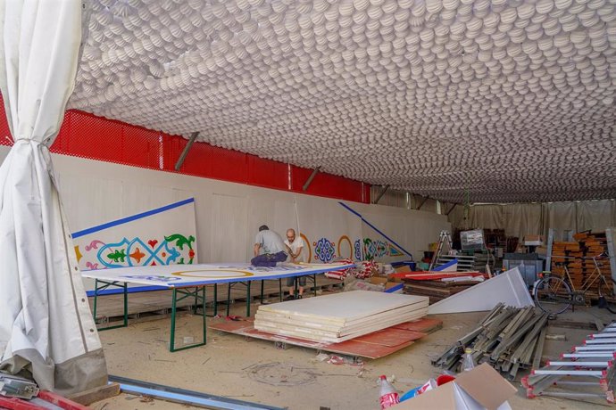 Archivo - Unos trabajadores en una caseta del recinto ferial donde se celebrará la Feria de Sevilla. 