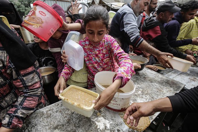 22 de abril de 2025, Nusairat, Faixa de Gaza, Território Palestino: Palestinos esperam em frente a um ponto de distribuição gratuita de alimentos para receber sua porção de uma refeição quente, no campo de refugiados de Nuseirat, no centro da Faixa de Gaz