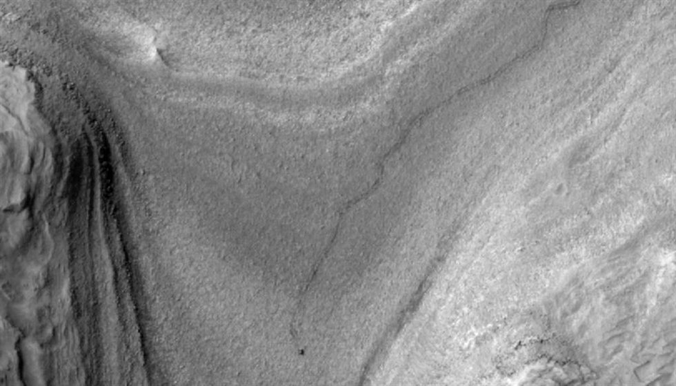 El rover Curiosity de la NASA aparece como una mancha oscura en esta vista de contraste mejorado capturada el 28 de febrero de 2025 por la cámara HiRISE a bordo del Mars Reconnaissance Orbiter de la NASA.