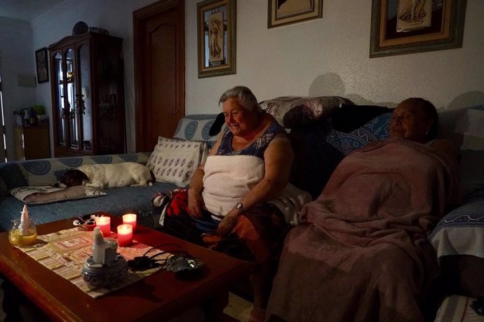 Una familia se ilumina con velas y se tapan con mantas en su casa durante el apagón eléctrico generalizado.