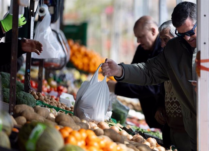 Archivo - Varias personas comprando en un mercado de alimentos