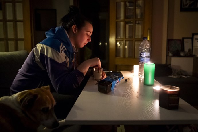 Una mujer se ilumina en el interior de su casa con la ayuda de velas e iluminación a pilas durante el apagón general, en Madrid, a 28 de abril de 2025