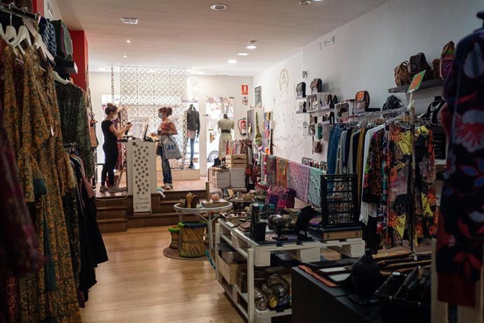 Archivo - Una trabajadora atiende a una clienta en su establecimiento comercial