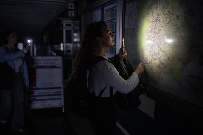 Una mujer ilumina con la linterna del móvil un plano de la red de Metro de Madrid en una estación, el 28 de abril de 2025 en Madrid, España.