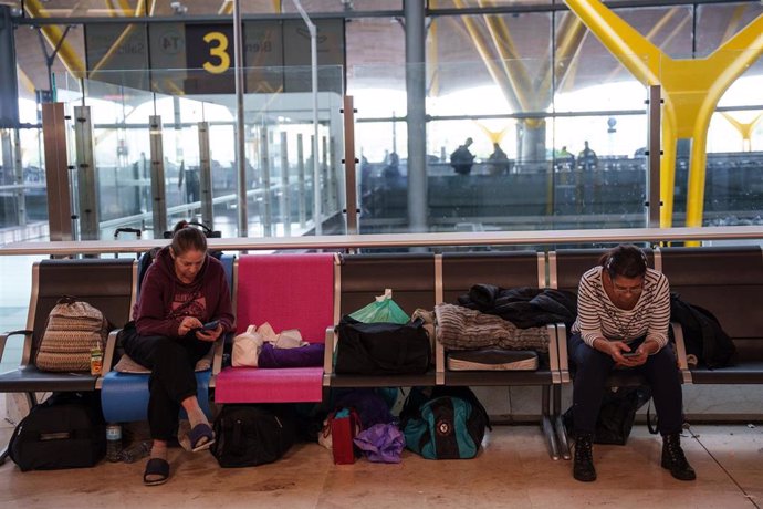 Varias personas sentadas en la terminal T4 del aeropuerto Adolfo Suárez-Madrid Barajas tras pasar un día del apagón eléctrico, a 29 de abril de 2025, en Madrid (España). 