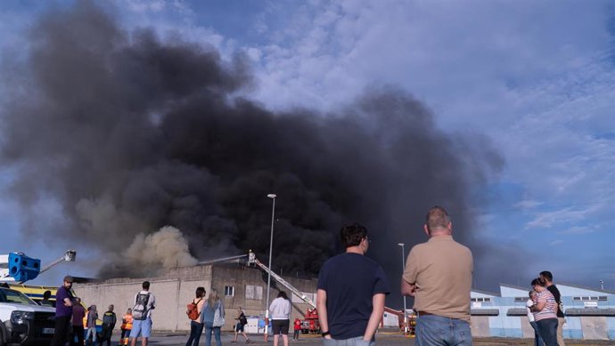 Varias personas observan el incendio de una nave, a 29 de abril de 2025, en Sada (A Coruña).
