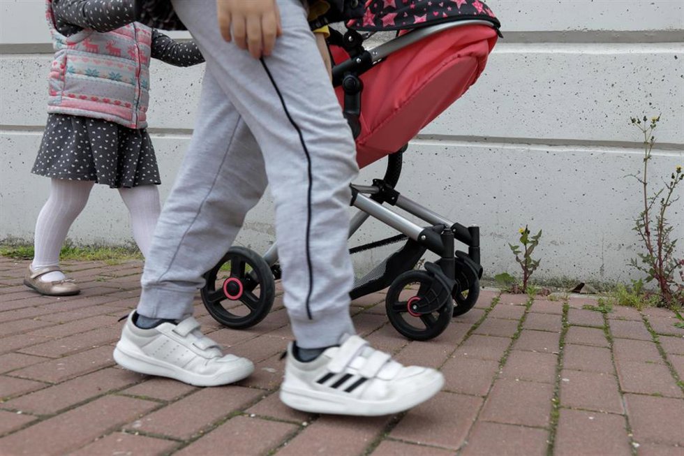 Archivo - Una niña pasea por la calle empujando un carrito con un bebé de juguete junto a su padre y su hermano. En Madrid (España) a 27 de abril de 2020.