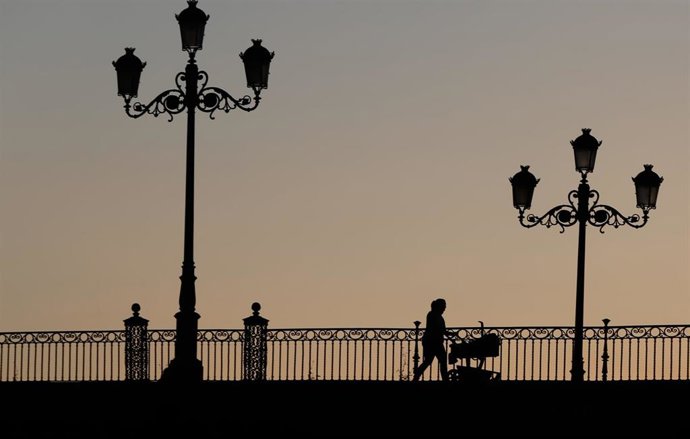 Archivo - Una madre con un carrito de bebe paseando al atardecer  por el Puente de Triana , en Sevilla a 28 de abril del 2020