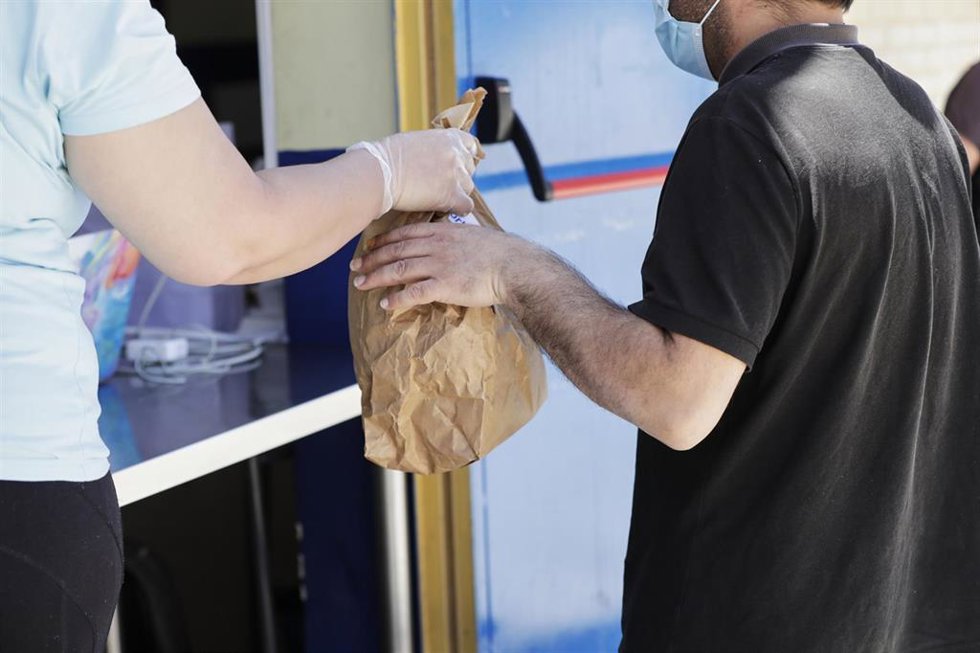 Archivo - Una voluntaria entrega una de las bolsas que contienen un menú de comida