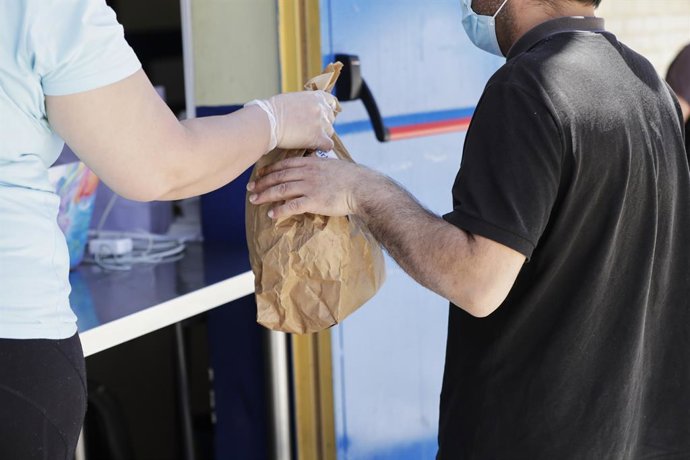 Archivo - Una voluntaria entrega una de las bolsas que contienen un menú de comida en el colegio Ramón María del Valle Inclán de San Blas, para que cada día de la semana puedan comer unas 800 personas, con alrededor de la entrega por el patio del colegio 