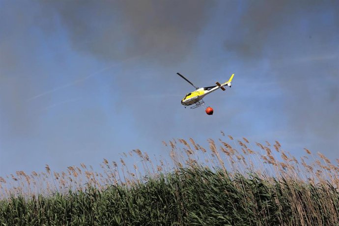 Archivo - Un helicóptero sobrevuela la zona afectada por un incendio.