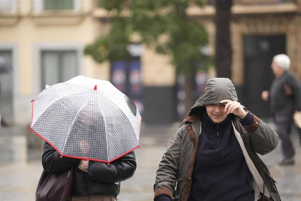 Archivo - Dos personas se protegen de la lluvia.