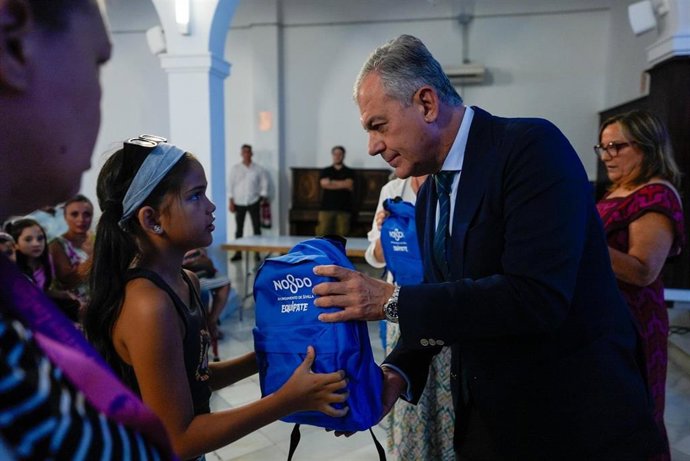 El alcalde de Sevilla entrega una mochila a una niña.