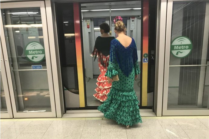 Mujeres vestidas de flamenca acceden al interior de uno de los vagones del metro.