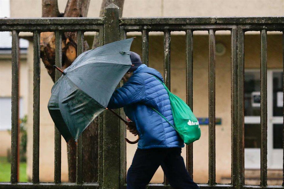 Archivo - Una persona se protege de la lluvia y el viento con un paraguas.