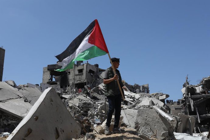 Archivo - Arquivo - Um jovem segura uma bandeira palestina sobre os restos de edifícios bombardeados por Israel na Faixa de Gaza.