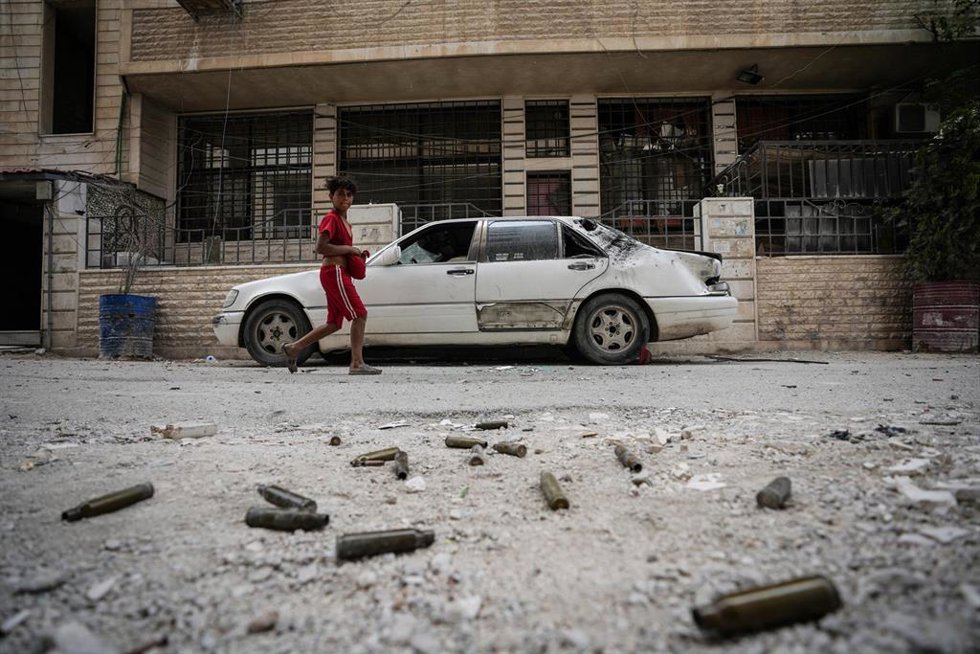 Un niño observa los cartuchos abandonados en el suelo tras enfrentamientos sectarios en Sahnaya, Siria