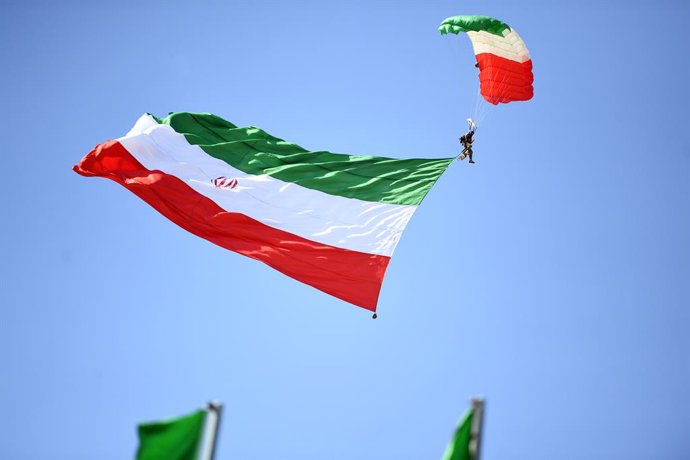 TEERÃ, 18 de abril de 2025 -- Um paraquedista carrega uma bandeira iraniana durante o desfile do Dia do Exército em Teerã, Irã, em 18 de abril de 2025.
