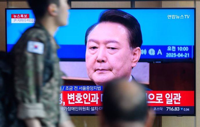 April 21, 2025, Seoul, South Korea: People look at a 24-hour Yonhap news TV broadcast at Seoul Railway Station showing a news broadcast with South Korea's former president Yoon Suk Yeol attending the second hearing of his insurrection trial at a courtroom