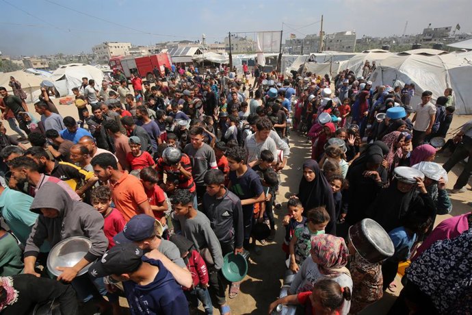 02 de maio de 2025, Territórios Palestinos, Cidade de Gaza: Os palestinos lutam para receber refeições quentes distribuídas por organizações de caridade em meio aos contínuos ataques israelenses e ao bloqueio total de Gaza. Foto: Omar Ashtawy/APA Images v
