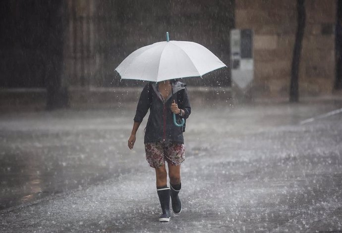 Archivo - Una persona camina con un paraguas bajo la lluvia en València. Imagen de archivo.