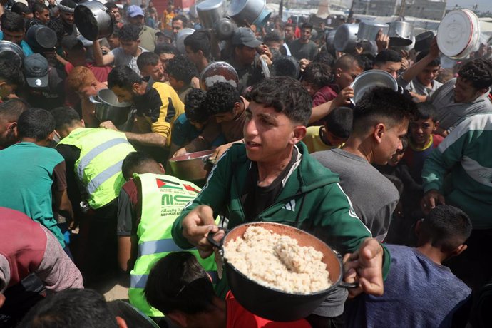 GAZA, May 2, 2025  -- Palestinians receive free food from a food distribution center in Gaza City, on May 2, 2025. The United Nations Relief and Works Agency for Palestine Refugees in the Near East (UNRWA) said Friday that the ongoing Israeli blockade is 