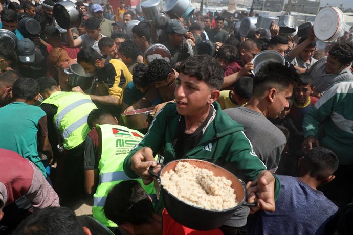 GAZA, 2 de maio de 2025 -- Palestinos recebem alimentos gratuitos de um centro de distribuição de alimentos na Cidade de Gaza, em 2 de maio de 2025. A Agência das Nações Unidas de Assistência aos Refugiados da Palestina no Oriente Próximo (UNRWA) disse na