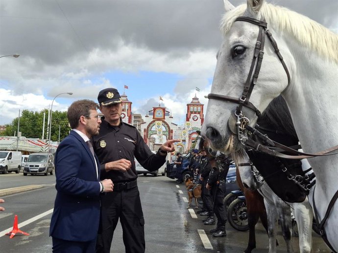 El subdelegado del Gobierno conversa con un agente de la Policía Nacional durante la presentación del dispositivo de seguridad para la Feria, con la portada al fondo.