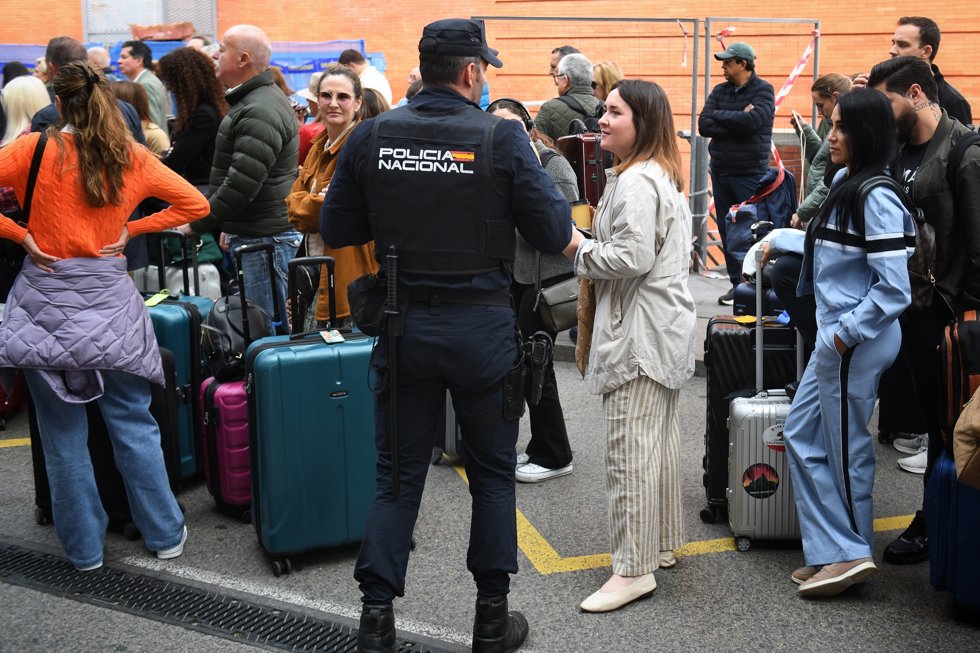 Un agente de Policía Nacional frente a varias personas en la estación de Atocha-Almudena Grandes, tras los retrasos en los trenes AVE, a 5 de mayo de 2025, en Madrid (España).