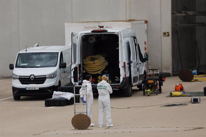 Dos agentes de Criminalística de la Guardia Civil dentro de la parcela de la nave, junto a la fosa séptica