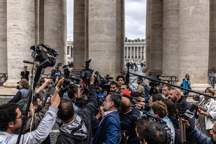 Un cardenal llega a la reunión rodeado de periodistas.