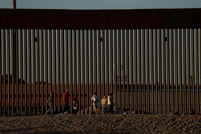 Archivo - Inmigrantes junto a la valla fronteriza levantada entre Estados Unidos y México (archivo)