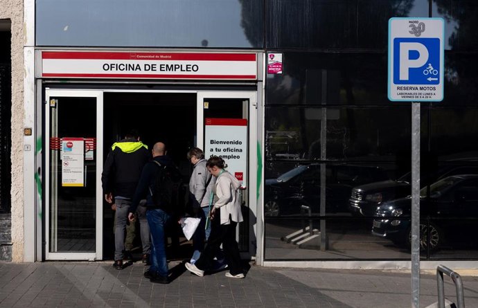 Archivo - Varias personas entrando en una oficina de empleo