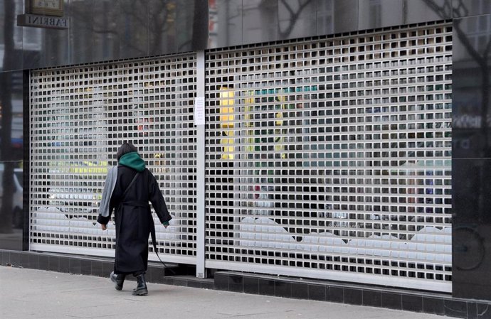 Archivo - 22 November 2021, Austria, Vienna: A passer-by walks past a closed shop. Since Monday 22 November 2021 Austria is in a fourth lockdown. Only shops for daily needs are open, cultural activities are at rest, museums and cinemas are closed. Photo: 
