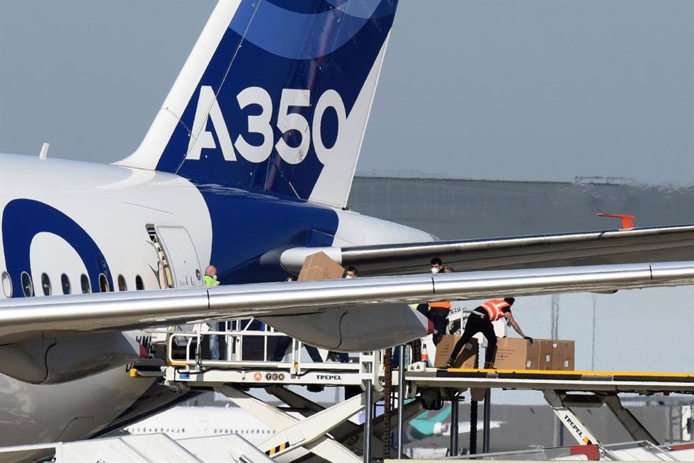 Archivo - 05 April 2020, France, Blagnac: Airport employees unload the cargo with protective masks from an Airbus A350-1000 at the "Toulouse-Blagnac" airport.
