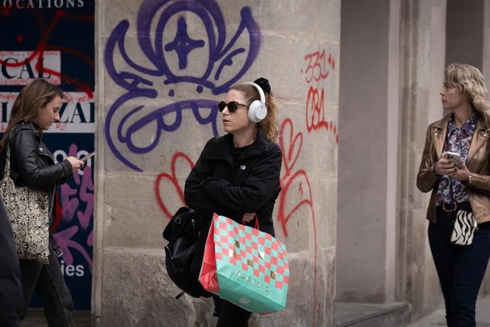 Archivo - Una mujer sujeta bolsas con compras durante la campaña de Navidad
