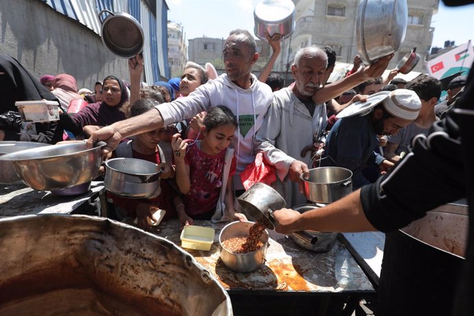 4 de maio de 2025, Nusairat, Faixa de Gaza, Território Palestino: Palestinos esperam em longas filas para receber potes de comida distribuídos por organizações de caridade, no campo de Nuseirat, no centro de Gaza, em 05 de maio de 2025. A crise alimentar 