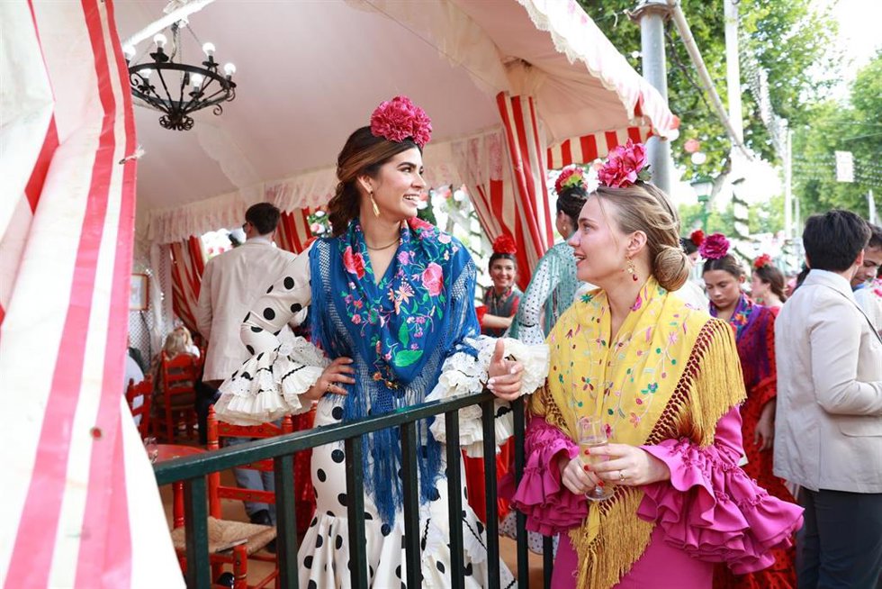 Mujeres vestidas de flamencas pasean por el real de la Feria de Abril de Sevilla.