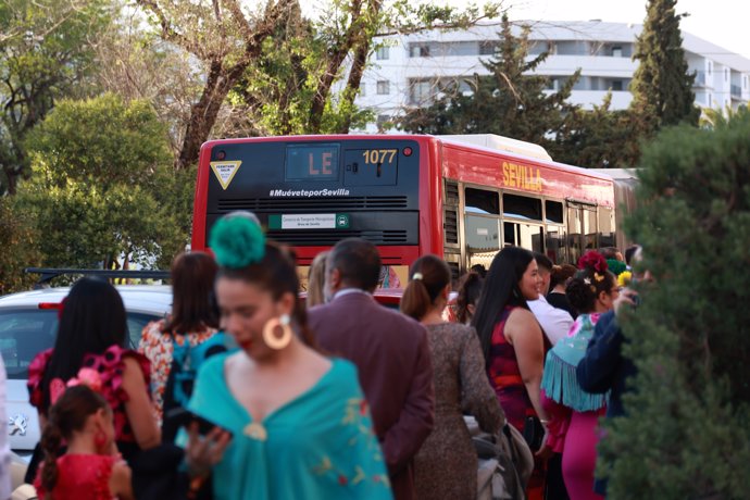 Usuarios hacen cola en la parada de autobús de la línea LE instalada en las inmediaciones del Real de la Feria de Abril.
