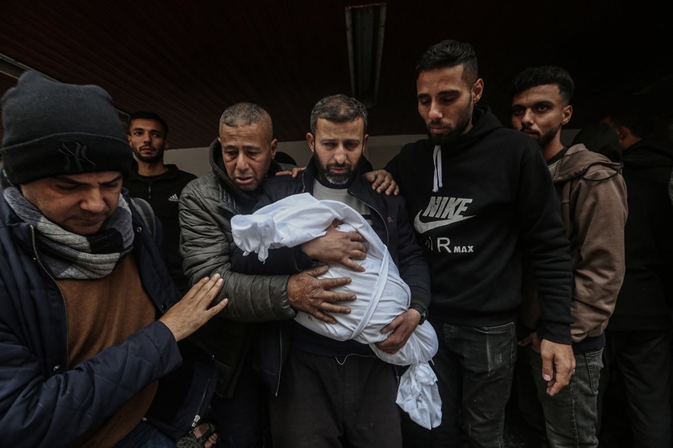 Varios palestinos llevan el cadáver de un niño que fue asesinado por un bombardeo israelí, en un hospital de Gaza.